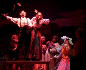 The evil overseer M'Closky (Richard Roberts Jr.) splatters money around in glee as he buys the Octoroon Zoe (Amanda Tavarez).