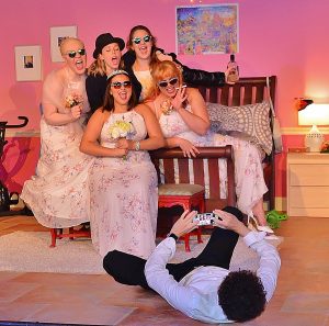 Tripp (Kevin Rubi) gets himself into what he feels is the best position to snap the perfect photograph of the reluctant bridesmaids. (Photo by Dennis Lyzniak)