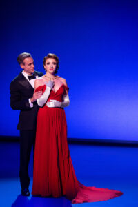 Edward Lewis (Adam Pascal) prepares Vivian Ward (Olivia Valli) for a night at the opera. (Photo by Matthew Murphy)